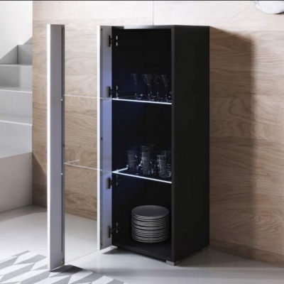 Móvel preto com porta de vidro aberto e prateleiras com copos e pratos em ambiente interior