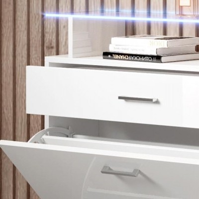 Móvel branco com gavetas e livros em cima, parede de madeira clara no fundo