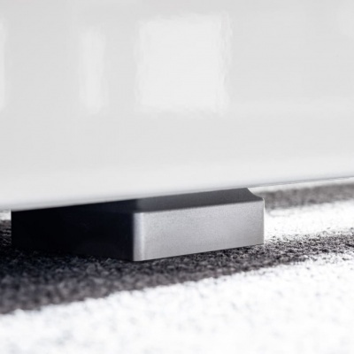 Base quadrada preta sob móvel branco em chão de carpete cinza