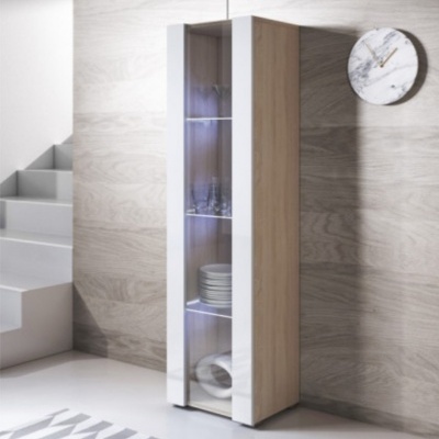 Móvel alto de madeira com porta de vidro, copos e pratos, ao lado de escada branca e parede com relógio