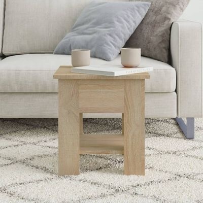 Mesa de apoio de madeira clara com canecas e livro, em frente a sofá cinza claro com almofadas