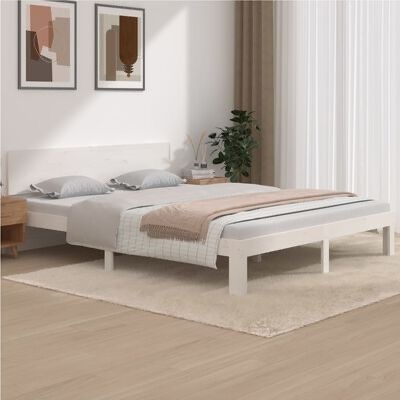 Cama branca de madeira com roupa de cama cinzenta e bege, sobre tapete bege, em quarto minimalista com quadros e plantas