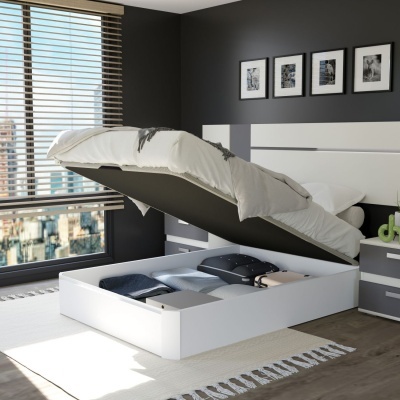 Cama branca com arrumação levantada num quarto moderno cinzento com janela e tapete branco