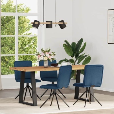 Mesa de jantar retangular em madeira com quatro cadeiras azuis numa sala iluminada com planta e candeeiro preto