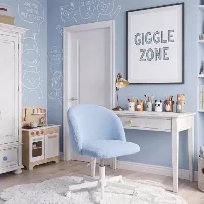Cadeira azul clara em quarto infantil com parede azul decorada e mesa branca.
