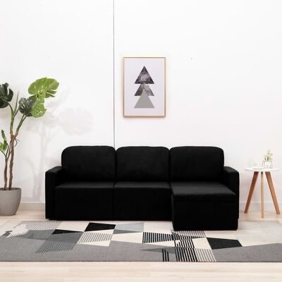 Sofá modular preto com chaise longue, carpete cinzento geométrico, quadro triângulos cinzentos, plantas e mesa de apoio