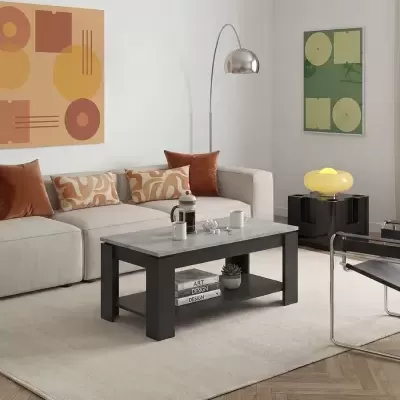 Sala de estar com mesa de centro retangular cinza e preta, sofá bege com almofadas castanhas, candeeiro de pé prateado e lâmpada amarela em mesa preta