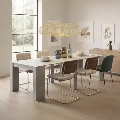 Mesa de jantar com cadeiras estofadas e luminária pendente decorativa em sala com janelas grandes e quadros