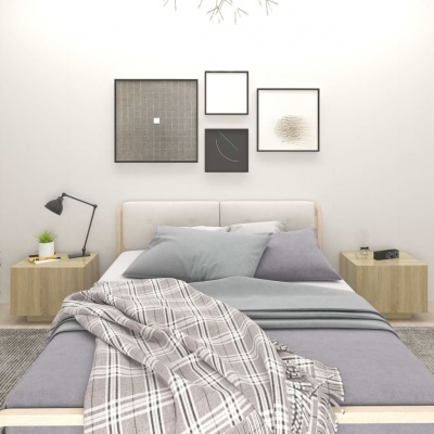 Cama com roupa de cama cinza e manta xadrez, duas mesas de cabeceira flutuantes, candeeiro, planta, relógio digital e quadros abstratos na parede branca