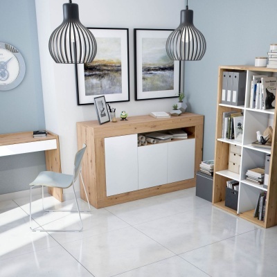 Sala de escritório moderna com móveis de madeira clara e detalhes brancos, cadeira cinza, e duas luminárias pretas pendentes.