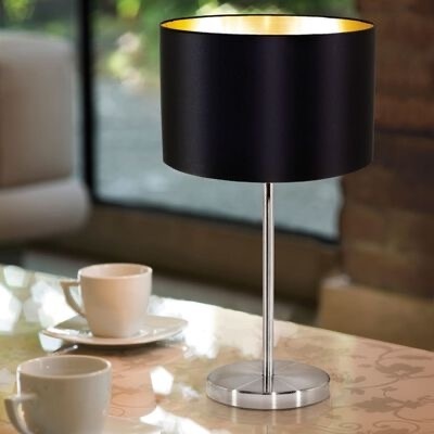 Candeeiro de mesa preto com interior dourado numa mesa com duas chávenas de café