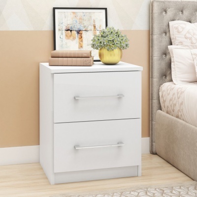 Mesa de cabeceira branca com dois livros, planta em vaso amarelo e quadro abstrato ao lado de cama cinza