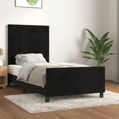 Cama individual preta com roupa de cama branca e cinza num quarto com planta e tapete cinza