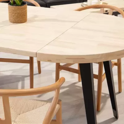 Mesa de madeira com tampo redondo e extensão, rodeada por cadeiras de madeira com assentos trançados