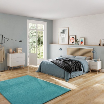 Quarto moderno com cama de casal com cabeceira de madeira clara, roupas de cama azuis, móvel e tapete azul