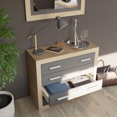 Cómoda de madeira clara com gavetas cinzentas e puxadores metálicos junto a parede cinzenta com espelho e planta