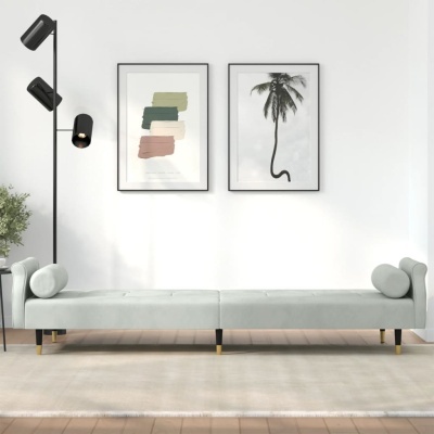 sofá cama cinza claro com apoios de braço cilíndricos e pernas douradas e pretas numa sala minimalista com candeeiro preto e quadros na parede