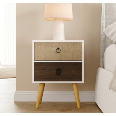 Mesa de cabeceira com duas gavetas bege e castanha, pés de madeira clara, lâmpada branca com abajur bege.