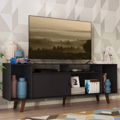 Móvel de apoio preto com TV, livros, moldura fotográfica, vasos e objetos decorativos em sala com parede geométrica
