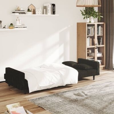 Sofá cama preto estendido numa sala moderna clara com estante de livros e tapete cinzento