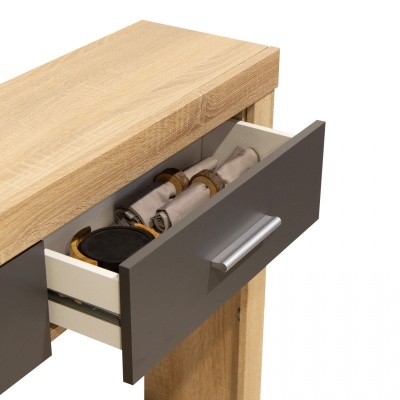 Gaveta cinza aberta de móvel em madeira clara com toalhas e objeto preto dentro