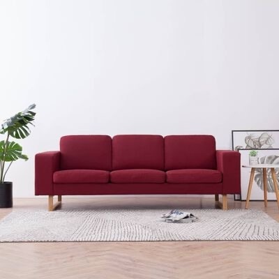 Sofá vermelho escuro de três lugares numa sala minimalista com tapete cinza, planta e mesa de apoio.