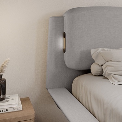 Cabeceira de cama cinzenta estofada com luz embutida e mesa de cabeceira com vaso e livros