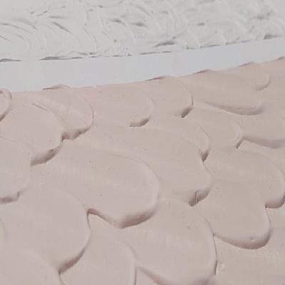 Superfícies texturizadas em relevo branco e rosa claro com padrões florais.