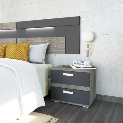 Mesa de cabeceira cinza escuro e madeira clara ao lado de cama com cabeceira cinza e almofadas amarelas