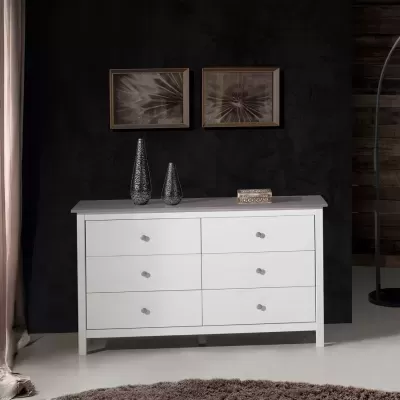 Cómoda branca de madeira com seis gavetas e decoração de vasos e caixa decorativa