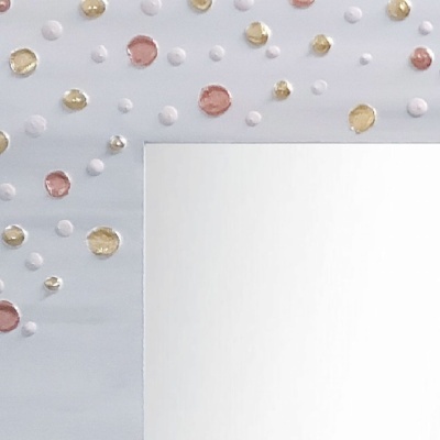 Espelho com moldura branca decorada com círculos coloridos em rosa, dourado e branco num fundo cinza.