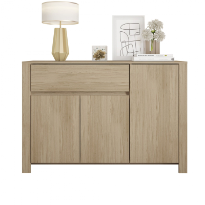 Aparador de madeira clara com candeeiro, moldura e flores em cima.