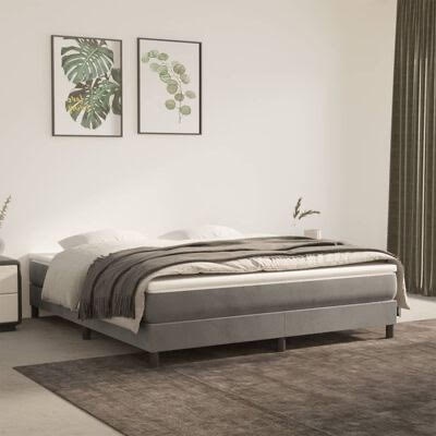 Cama dupla estofada cinza com roupa de cama branca e manta cinza, tapete castanho e decoração de parede com quadros de folhas