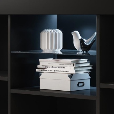 Prateleira preta com caixa branca, livros e objetos decorativos em cerâmica branca e preta