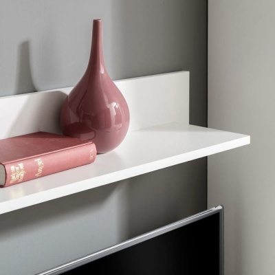 estante branca com vaso rosa e livro vermelho sobre parede cinzenta e ecrã preto abaixo