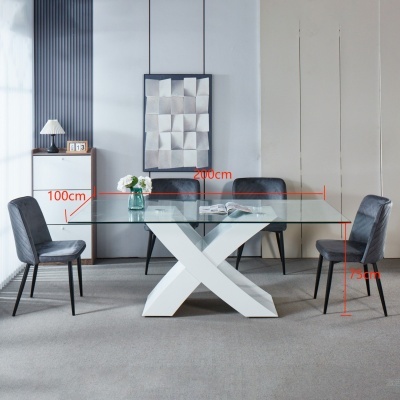 Mesa de jantar com tampo em vidro, base branca cruzada, quatro cadeiras cinzentas e medidas visíveis.