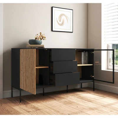 Móvel buffet preto com portas de madeira clara e gavetas, numa sala iluminada com janela e quadro abstrato.