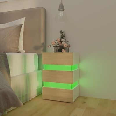 Criado-mudo em madeira clara com iluminação verde ao lado de cama e lâmpada pendente