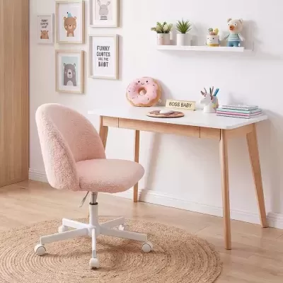 Cadeira rosa e mesa branca com decoração infantil e quadros na parede