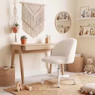 Escritório claro com mobília de madeira, cadeira branca peluda, tapete natural e decoração em macramê.