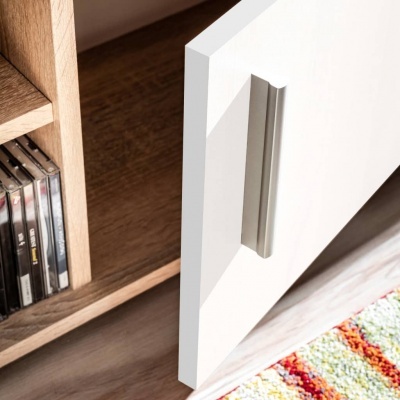 Porta branca de armário com puxador prateado, prateleira em madeira com CDs e tapete colorido no chão