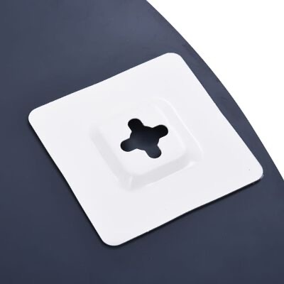 Peça metálica branca quadrada com orifício em cruz no centro sobre superfície escura