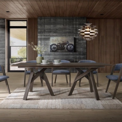 Sala de jantar com mesa de madeira escura e cadeiras azuis cinzentas, quadro de motocicleta e candeeiro pendente moderno.