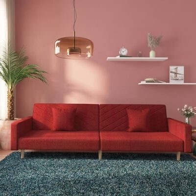 Sofá vermelho numa sala com parede cor-de-rosa e prateleiras brancas com decoração