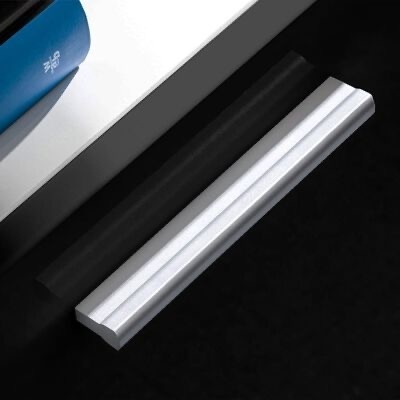 Dois objetos retangulares, um azul e outro prateado, sobre superfícies preta e branca.