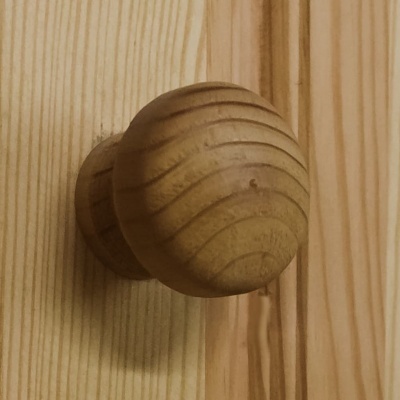 Puxador de porta de madeira redondo numa porta de madeira clara