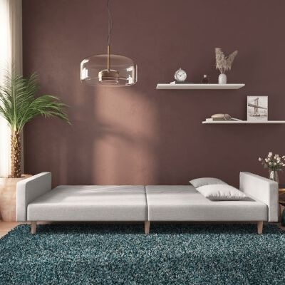 Sofá-cama cinza claro com decoração em parede castanha e tapete azul-escuro