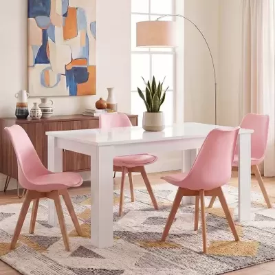 Conjunto de mesa branca com quatro cadeiras cor-de-rosa numa sala de jantar iluminada e decorada com móvel, quadro, planta e candeeiro