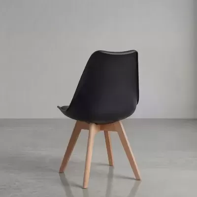 Cadeira preta com pernas de madeira clara num ambiente minimalista cinzento