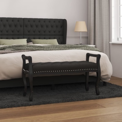 Banco preto estofado com tachinhas decorativas ao pé de cama com cabeceira preta
